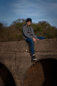 Full length of young man skateboarding on land against sky