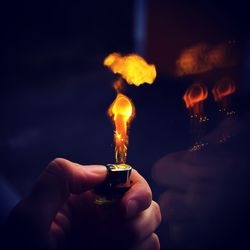 Cropped hand igniting cigarette lighter in darkroom