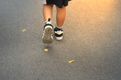 Low section of boy walking on road