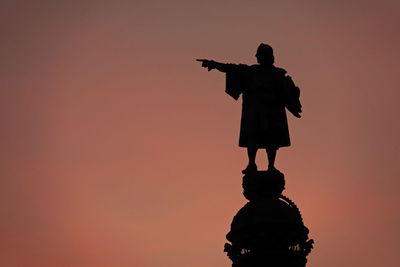 Rear view of silhouette people standing against orange sky