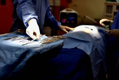 Midsection of doctors performing surgery on patient in hospital