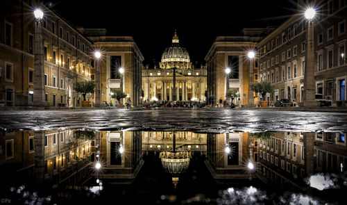 Reflection of illuminated cathedral in puddle on street at night