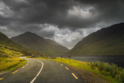Road leading trough doolough valley beside lake and between mountain ranges, ireland