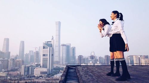 Woman standing by buildings against sky in city