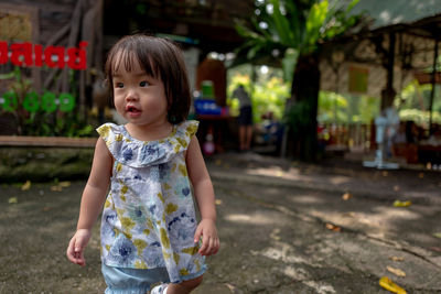 Cute toddler girl standing on footpath