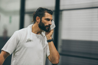 Man playing padel tennis wipes the sweat. sporty boy at the end of the match. sweaty barded athlete 