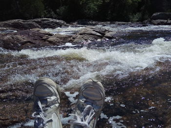Low section of person standing by stream