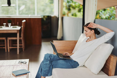 Young woman using mobile phone while sitting in cafe