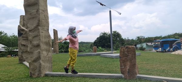 Full length of woman walking on grass against sky