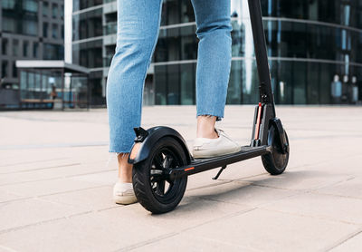 Unrecognizable woman standing on an electric scooter in the city	