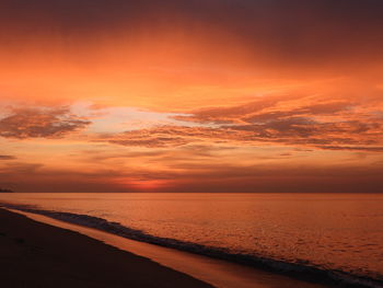 Scenic view of sea against dramatic sky during sunset