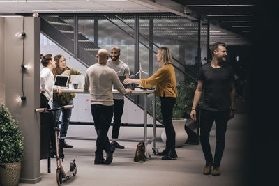 Business professionals discussing over renewable sources while standing at desk in office