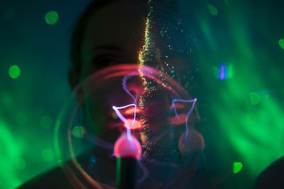 Close-up portrait of young woman against illuminated background