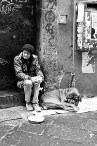 Full length of man sitting on sidewalk