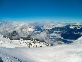 Scenic view of snow covered mountains against blue sky