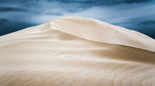 Sand dunes in desert against sky