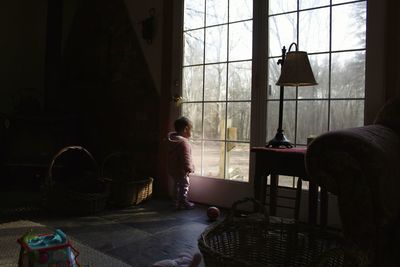 Baby girl looking through window at home