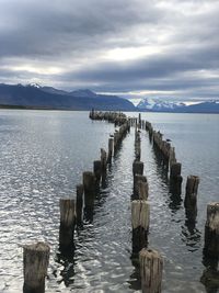 Wooden posts in sea against sky