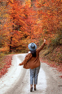 Rear view of woman on path in forest, fall colors, autumn, style, influencer.