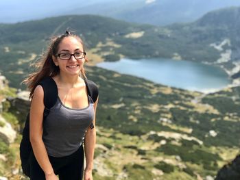 Portrait of smiling young woman standing on mountain