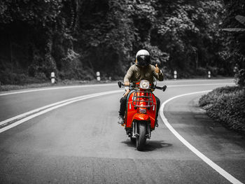 Rear view of people riding motorcycle on road