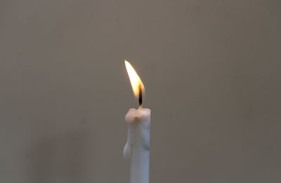 Close-up of burning candle against gray background