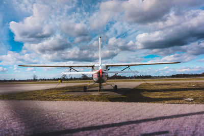 Biplane on runway against cloudy sky