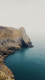 Rock formations by sea against clear sky