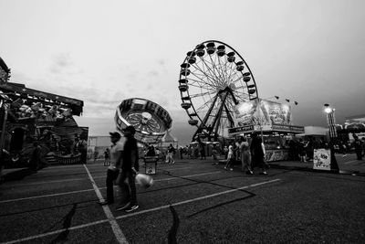 People in amusement park against sky in city