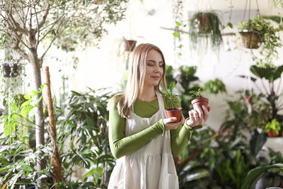 Young woman standing by plants against trees