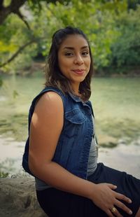 Portrait of young woman sitting by river