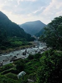 Scenic view of river by mountains against sky