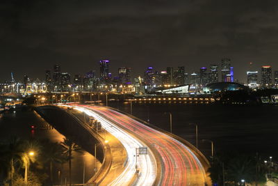 High angle view of light trails on road amidst buildings at night