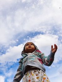 Low angle view of girl looking up against sky