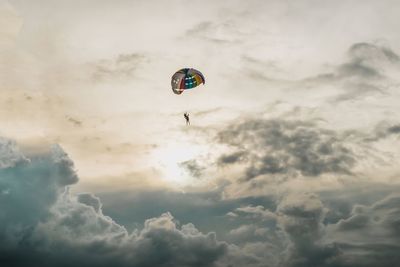 Low angle view of person paragliding against sky