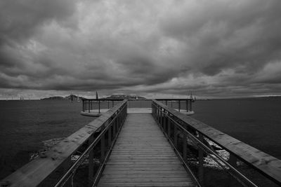 Pier in sea against cloudy sky