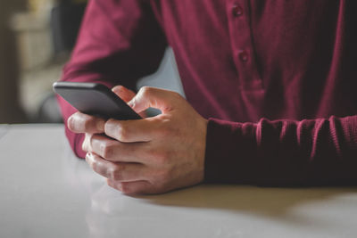 Midsection of man using mobile phone at table