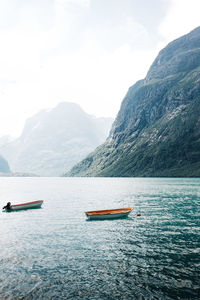 Sailboats in sea against mountains