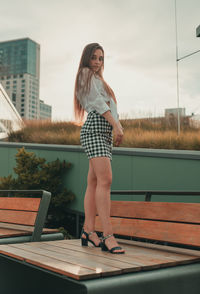 Portrait of woman standing on wooden bench