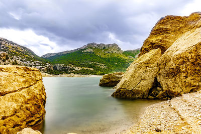 Rock formation by sea against sky