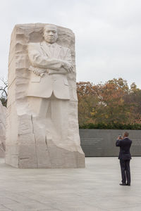 Statue of man and woman standing against sky