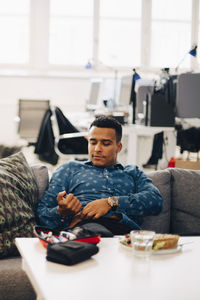 Businessman injecting insulin while sitting on sofa in office