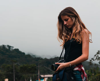 Young woman standing against sky