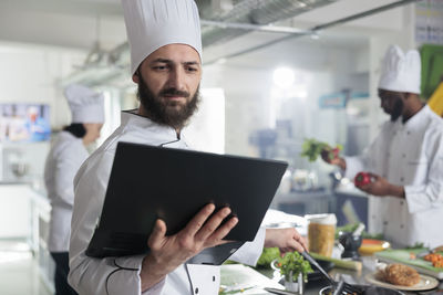 Bearded chef using laptop in kitchen