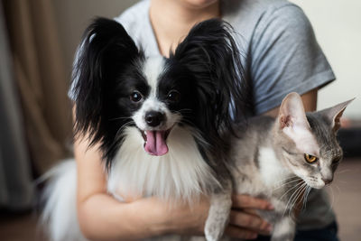 Midsection of woman holding cat and dog at home