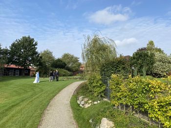 People on footpath by trees against sky