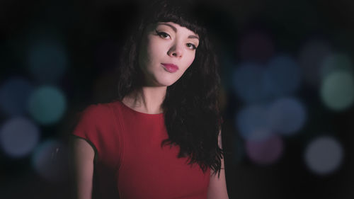 Portrait of young woman against black background