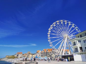 Low angle view of ferris wheel against blue sky