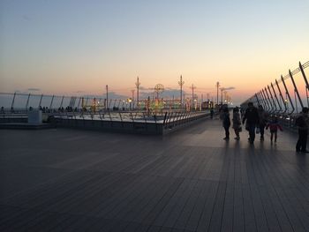 People on beach against clear sky during sunset