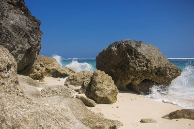 Rocks on beach against clear blue sky